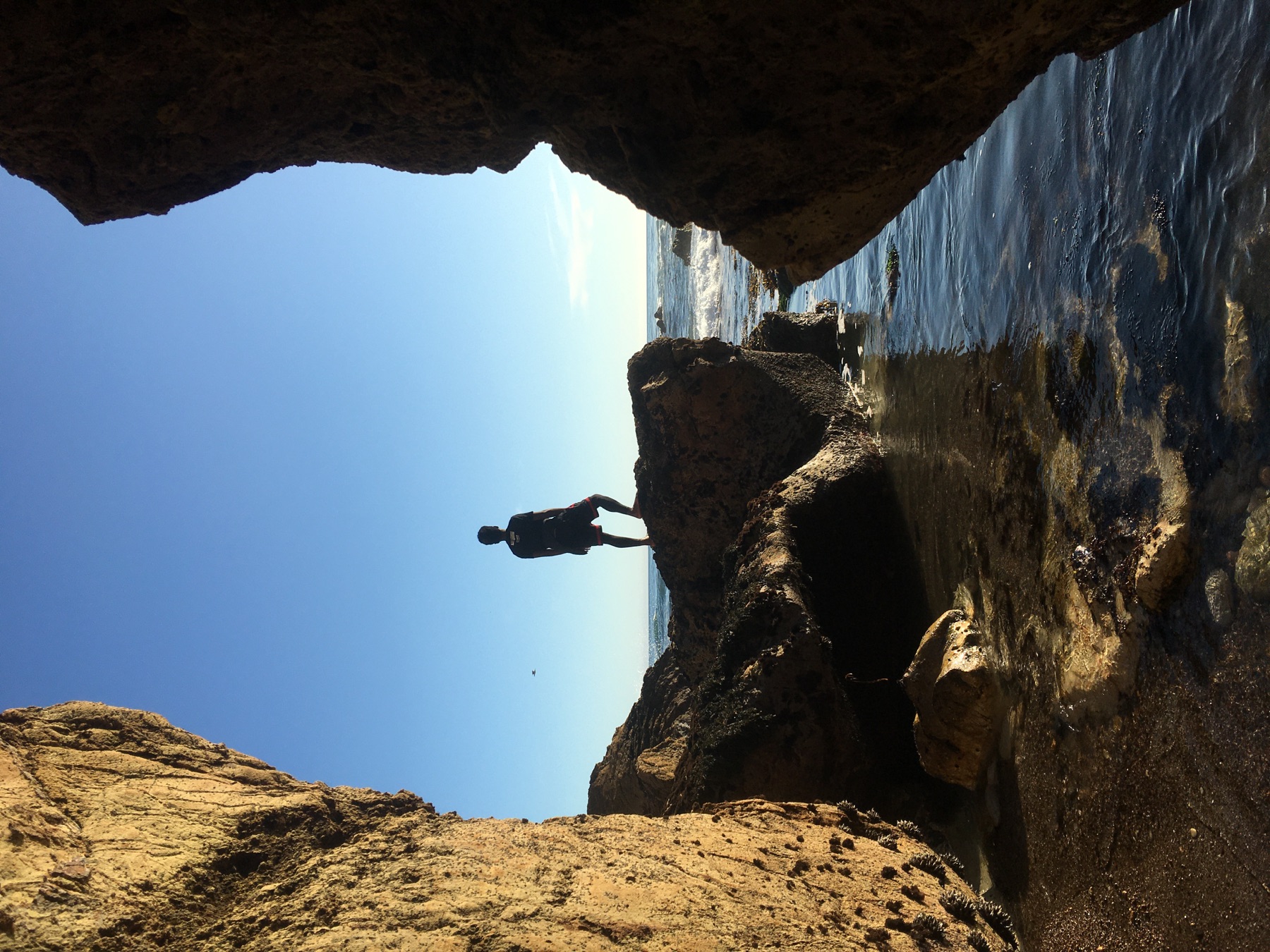Yannick Matia looking out over the Pacific Ocean from a rocky cove