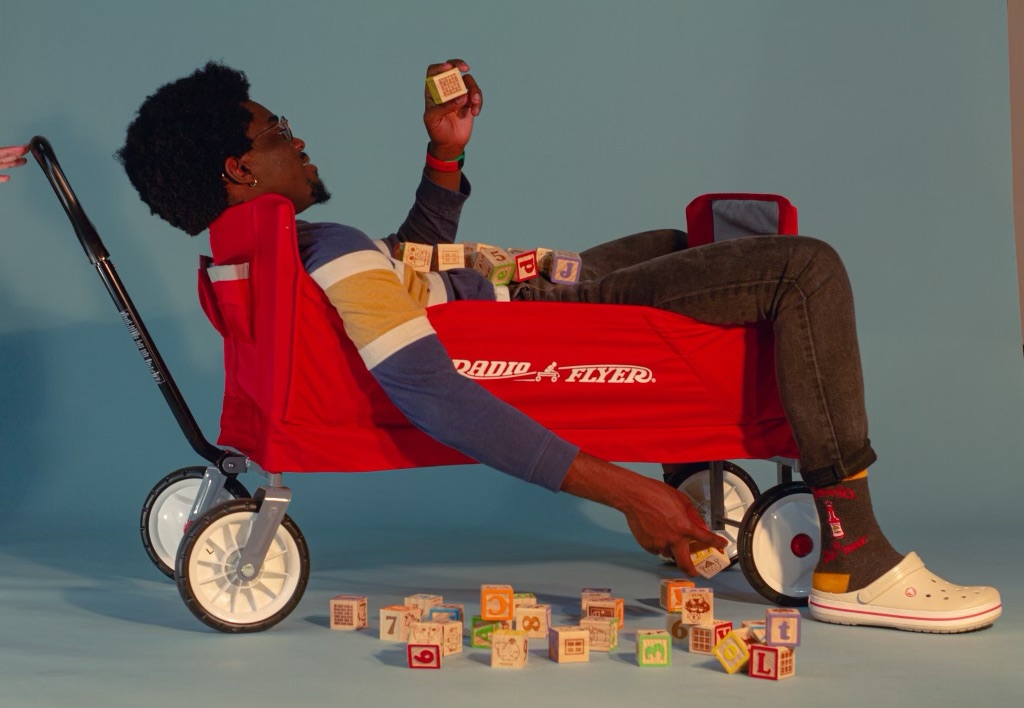 Yannick Matia playfully reclining in a red wagon surrounded by alphabet blocks